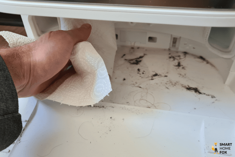 The dirt in the cleaning tray of the Dreame L10s Ultra base station is removed with a wipe.